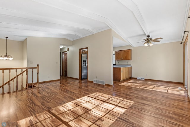 unfurnished living room with ceiling fan with notable chandelier, lofted ceiling with beams, and light wood-type flooring