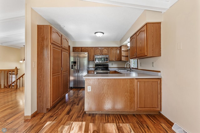 kitchen featuring beamed ceiling, sink, kitchen peninsula, dark wood-type flooring, and stainless steel appliances