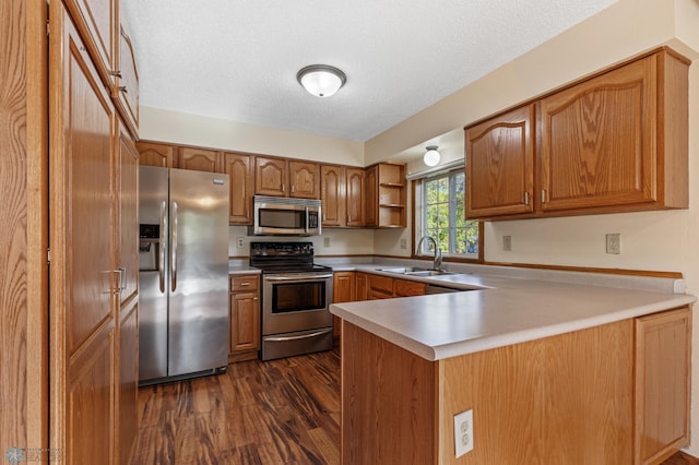 kitchen featuring sink, dark hardwood / wood-style flooring, kitchen peninsula, appliances with stainless steel finishes, and a textured ceiling