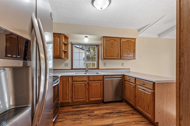 kitchen featuring beam ceiling, sink, dark hardwood / wood-style floors, appliances with stainless steel finishes, and a textured ceiling