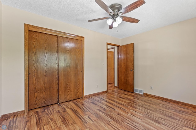 unfurnished bedroom with a closet, light hardwood / wood-style floors, a textured ceiling, and ceiling fan