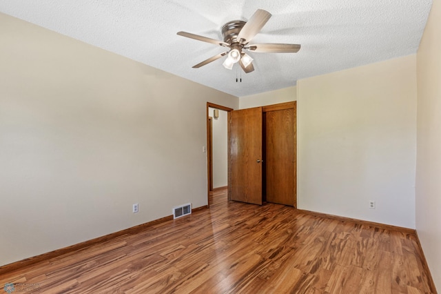 unfurnished bedroom with hardwood / wood-style flooring, ceiling fan, a closet, and a textured ceiling