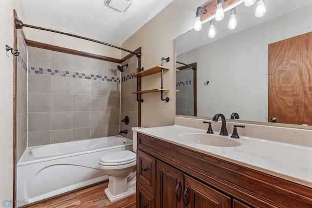 full bathroom featuring vanity, toilet, tiled shower / bath combo, a textured ceiling, and hardwood / wood-style floors