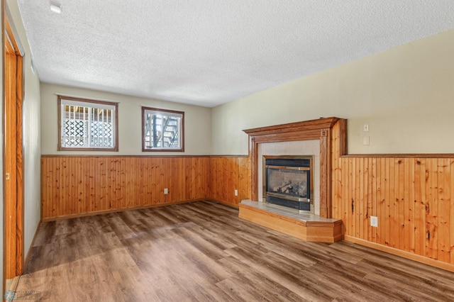 unfurnished living room featuring wooden walls, a textured ceiling, a fireplace, and hardwood / wood-style floors