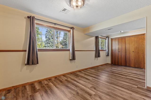 interior space with a closet, hardwood / wood-style floors, multiple windows, and a textured ceiling