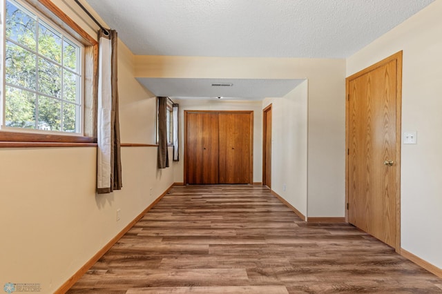 hallway with wood-type flooring and a textured ceiling