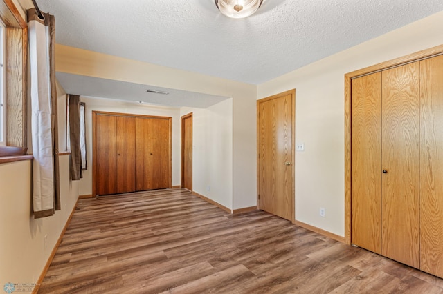 hall with wood-type flooring and a textured ceiling