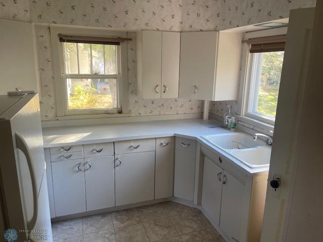 kitchen featuring white fridge, a healthy amount of sunlight, and white cabinetry