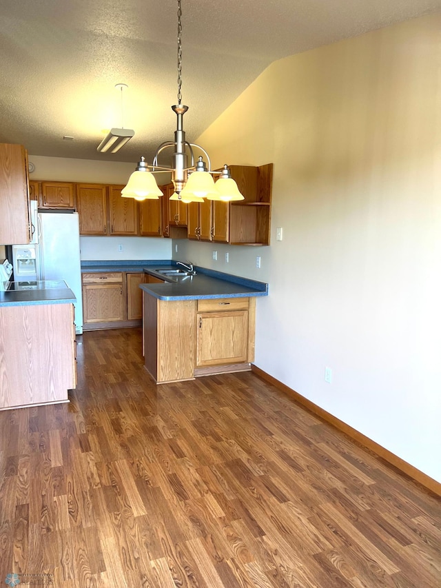 kitchen with lofted ceiling, hanging light fixtures, kitchen peninsula, sink, and dark hardwood / wood-style flooring