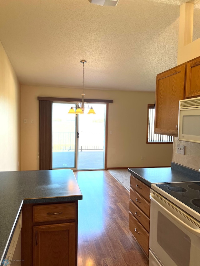 kitchen with white appliances, dark wood-type flooring, decorative light fixtures, a notable chandelier, and a textured ceiling