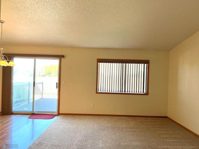 unfurnished room with an inviting chandelier, a textured ceiling, and hardwood / wood-style flooring