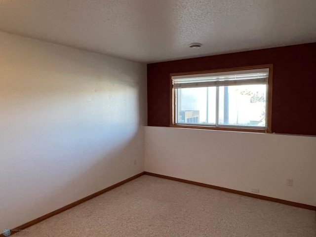 carpeted spare room with a textured ceiling