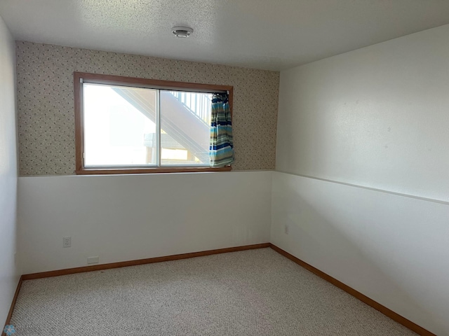 carpeted empty room featuring plenty of natural light and a textured ceiling