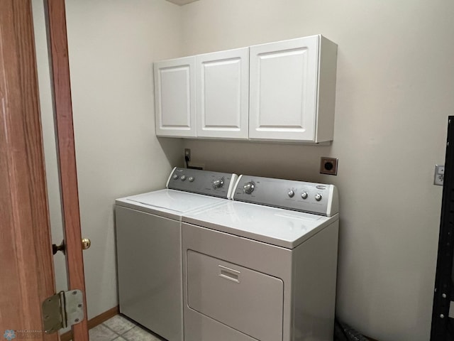 clothes washing area with cabinets, light tile patterned floors, and washing machine and clothes dryer