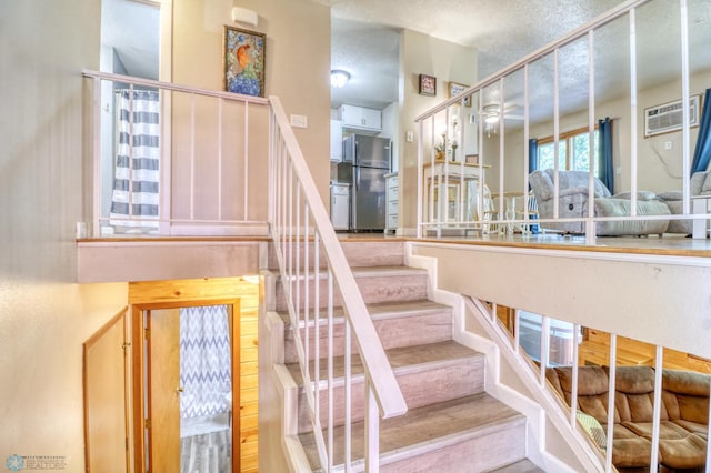 stairs with a wall unit AC and a textured ceiling