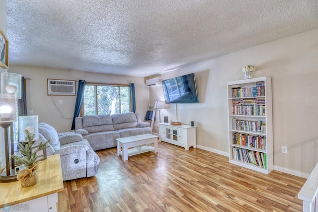 living room featuring light wood-type flooring, a wall mounted AC, and a textured ceiling