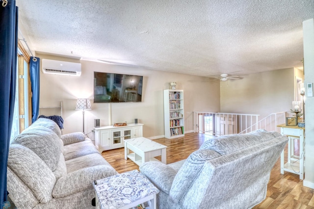 living room featuring a textured ceiling, light hardwood / wood-style floors, and a wall mounted AC