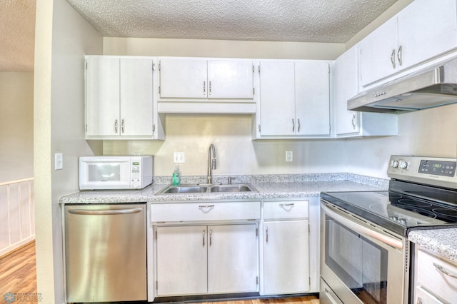 kitchen featuring light wood-type flooring, white cabinets, sink, appliances with stainless steel finishes, and a textured ceiling