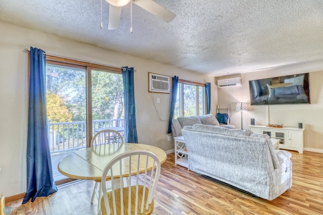 living room with an AC wall unit, light wood-type flooring, and a healthy amount of sunlight