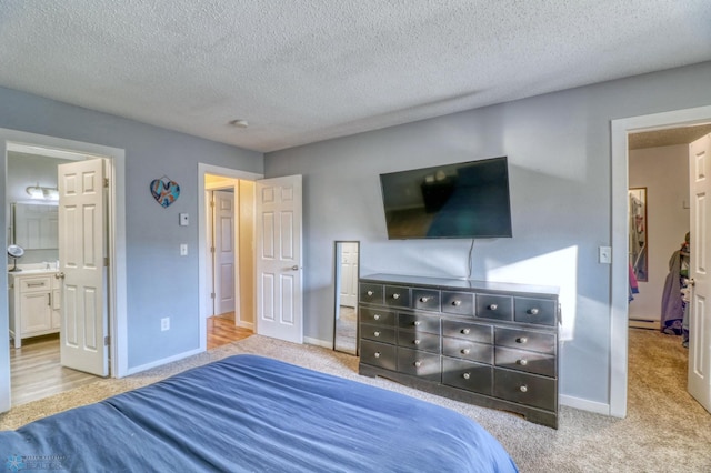 bedroom featuring light carpet, a textured ceiling, and ensuite bathroom