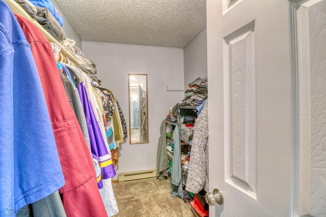 walk in closet with a baseboard heating unit and carpet