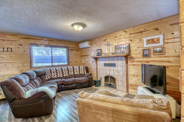 living room with hardwood / wood-style flooring, a tiled fireplace, and wood walls