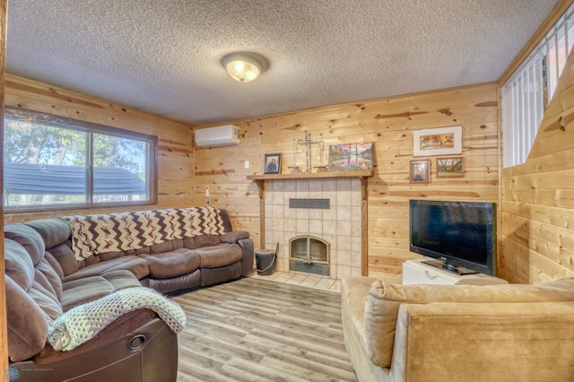 living room with wood walls, a textured ceiling, hardwood / wood-style flooring, a fireplace, and an AC wall unit