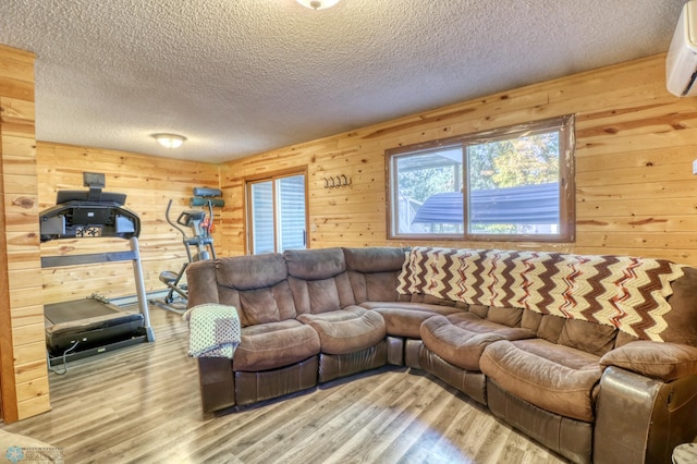 living room with wooden walls, light hardwood / wood-style flooring, and a textured ceiling