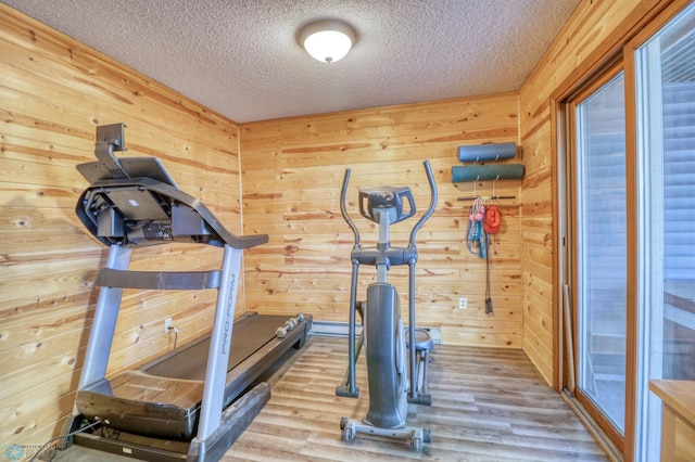 workout room featuring a textured ceiling, light hardwood / wood-style flooring, and wood walls