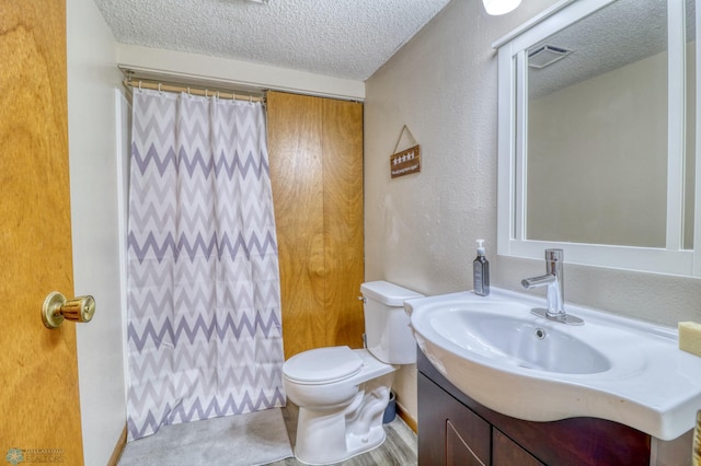 bathroom featuring a textured ceiling, a shower with shower curtain, vanity, and toilet