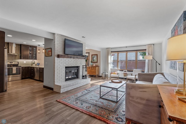 living room with a fireplace, sink, and wood-type flooring