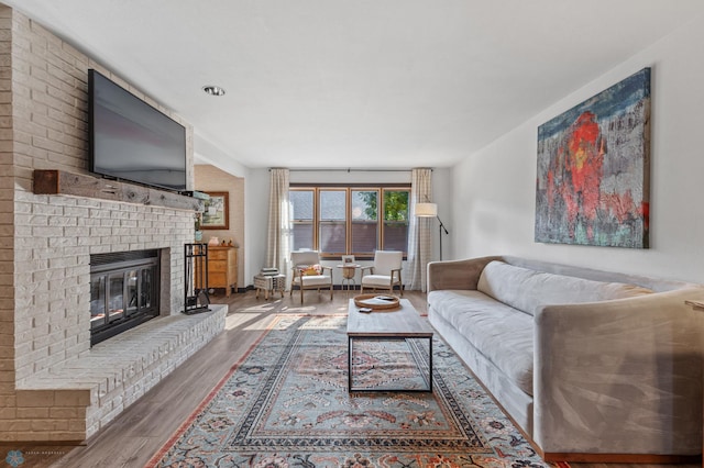 living room with hardwood / wood-style flooring and a brick fireplace