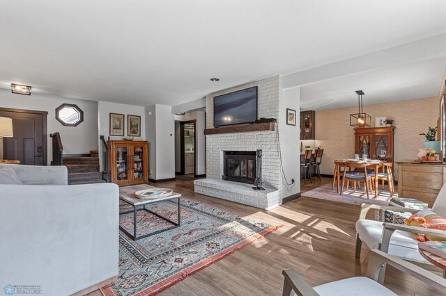 living room with wood-type flooring and a brick fireplace