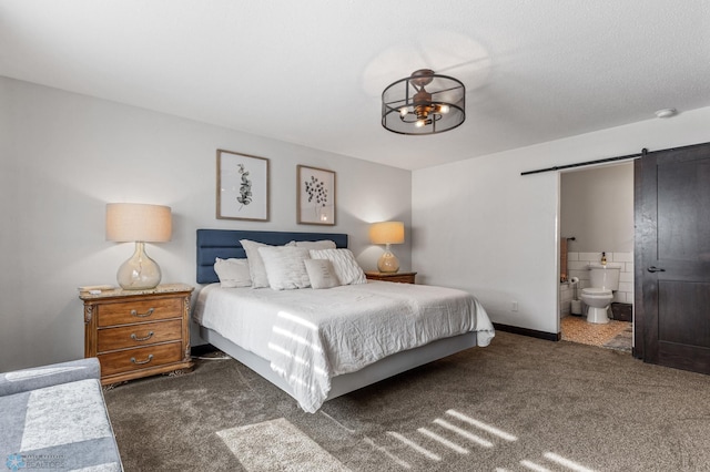 carpeted bedroom featuring a barn door, a textured ceiling, and ensuite bath