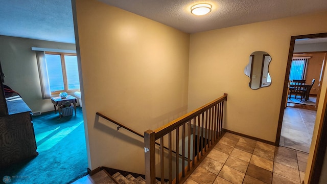 stairs featuring a textured ceiling and carpet flooring