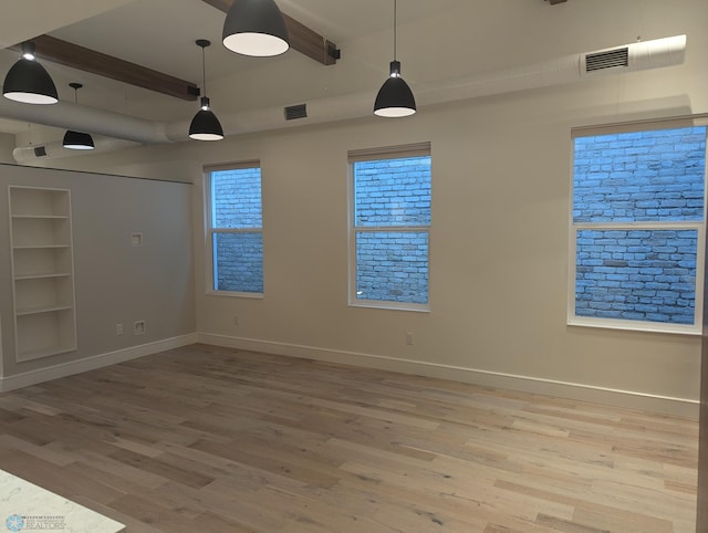 empty room featuring wood-type flooring and beamed ceiling