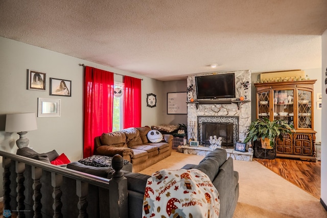 living room with a stone fireplace, hardwood / wood-style flooring, and a textured ceiling