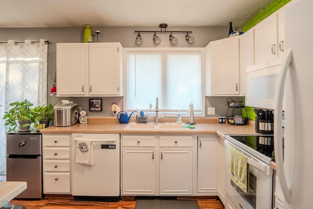 kitchen featuring white appliances, sink, dark hardwood / wood-style floors, white cabinets, and a textured ceiling