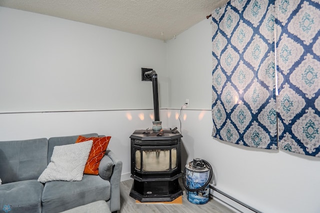 interior space with a wood stove, a baseboard radiator, wood-type flooring, and a textured ceiling