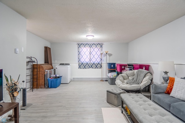 living room with washer / clothes dryer, a textured ceiling, light hardwood / wood-style flooring, and a baseboard radiator