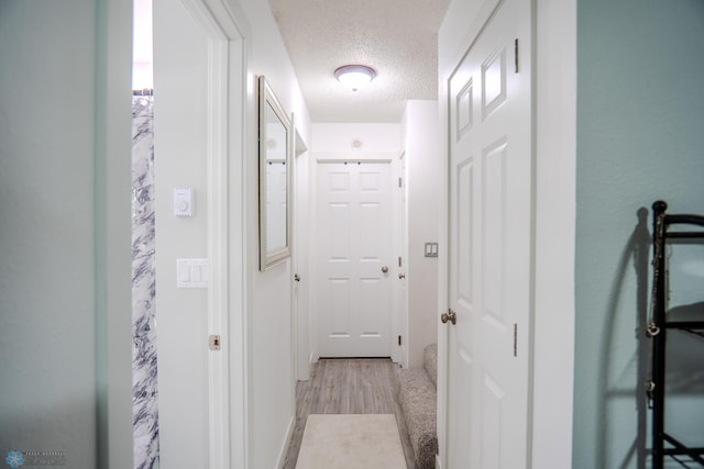 hall featuring light hardwood / wood-style floors and a textured ceiling