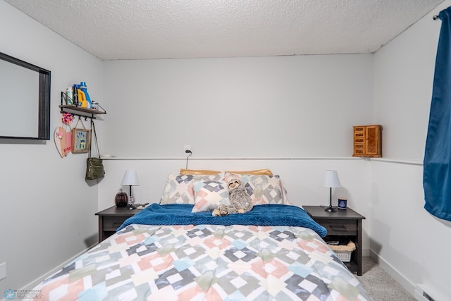 carpeted bedroom featuring a baseboard heating unit and a textured ceiling