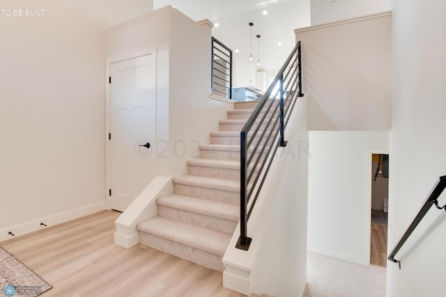 stairway featuring hardwood / wood-style flooring and a towering ceiling