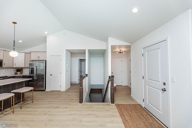 kitchen with light hardwood / wood-style floors, decorative light fixtures, vaulted ceiling, and stainless steel appliances