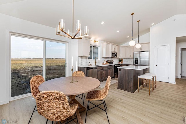 dining space featuring an inviting chandelier, light wood-type flooring, and high vaulted ceiling