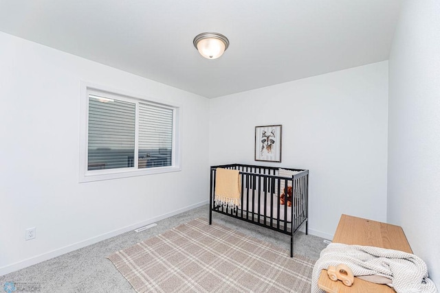 bedroom featuring light carpet and a nursery area