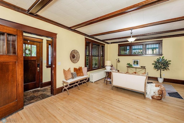 foyer with ornamental molding, beamed ceiling, light wood-type flooring, and radiator