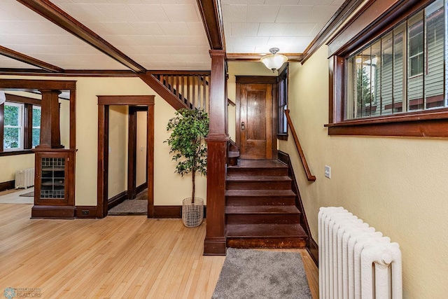 staircase with radiator heating unit, crown molding, and hardwood / wood-style flooring