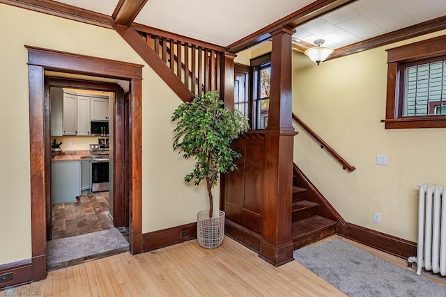 foyer entrance featuring ornamental molding, radiator heating unit, and light hardwood / wood-style flooring