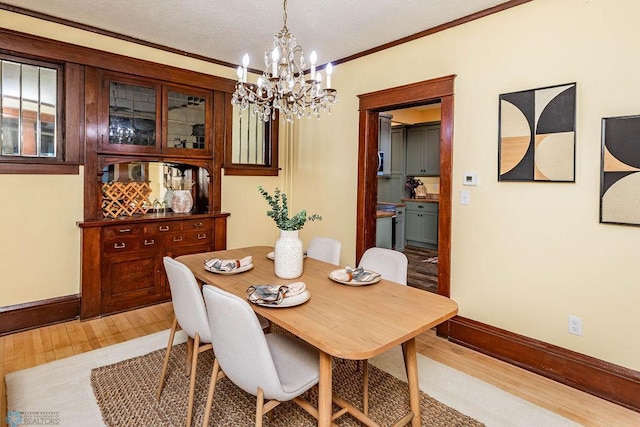 dining space with light hardwood / wood-style floors, crown molding, an inviting chandelier, and a textured ceiling